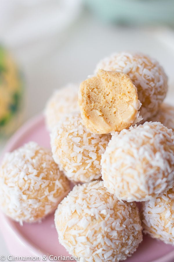 no bake passionfruit cheesecake bites rolled in coconut on a small pink plate