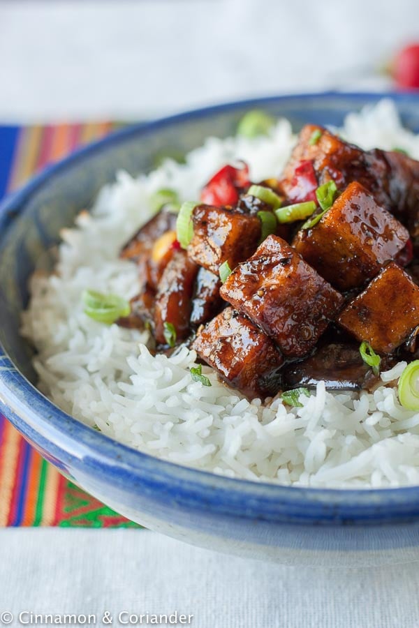 side view of vegan black pepper tofu served over a bed of white rice
