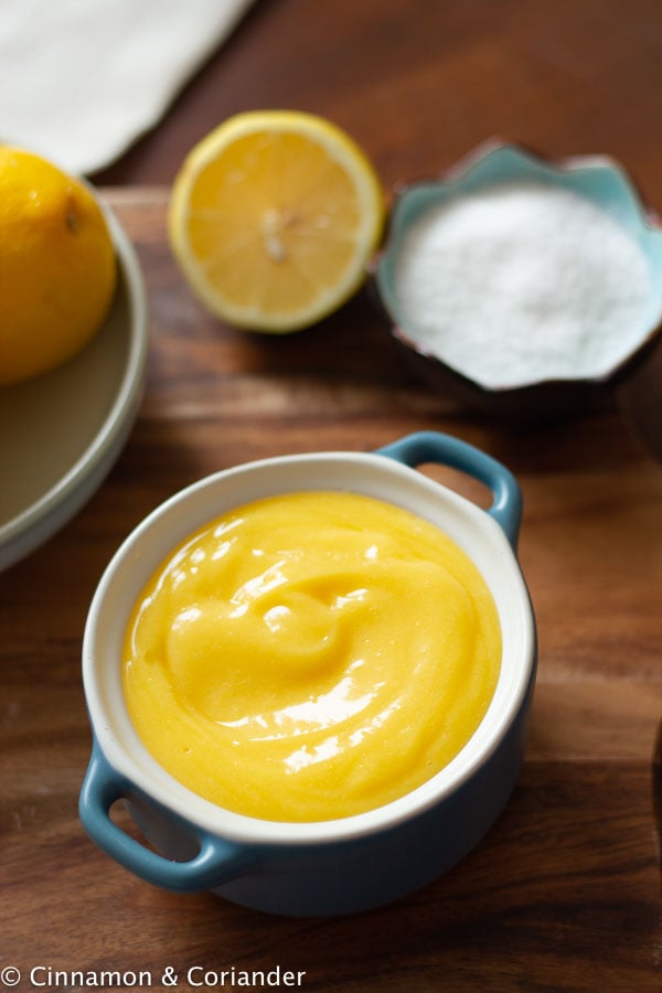 a small bowl with sugar-free low carb lemon curd with lemons in the back