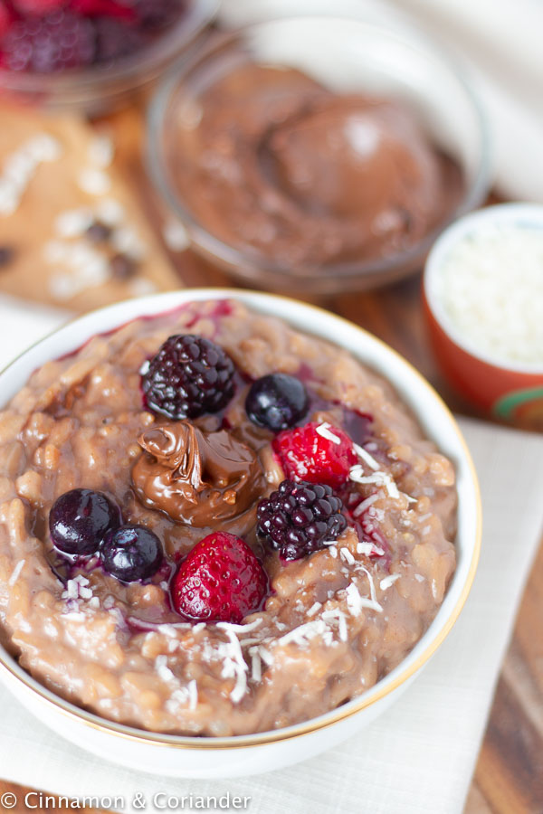 a bowl with creamy Instant Pot Rice Pudding with Nutella decorated with berries and coconut