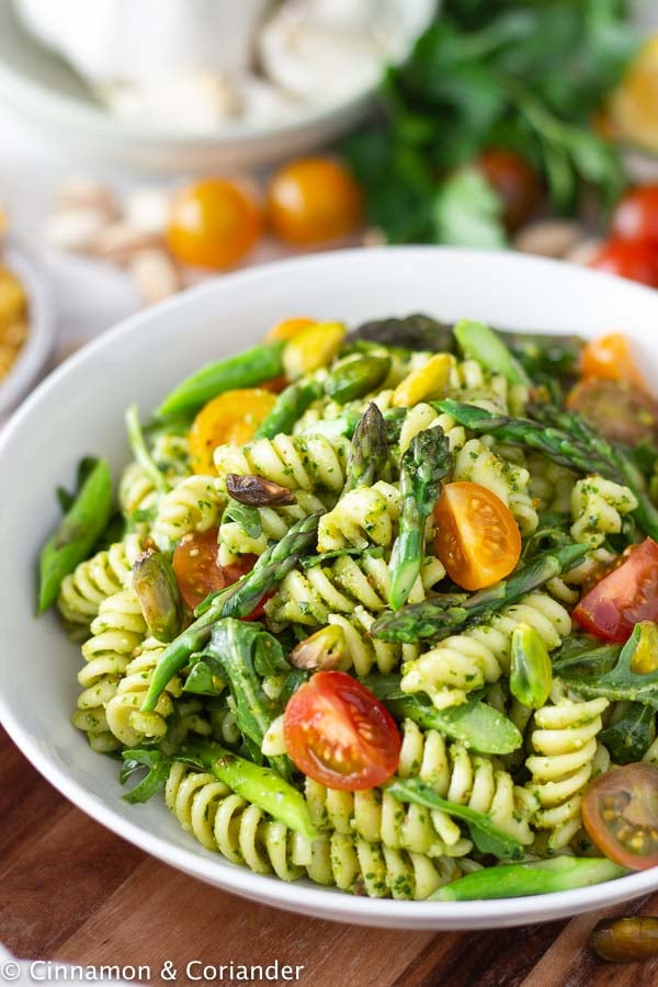 close-up of a serving of pistachio pesto pasta salad with tomatoes and asparagus