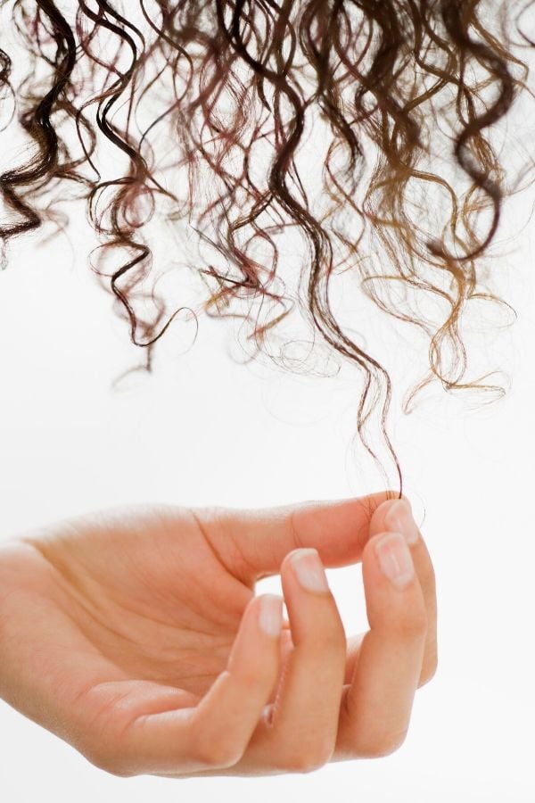 eine Frau massiert sich Locken Leinsamengel in die feuchten Naturlocken