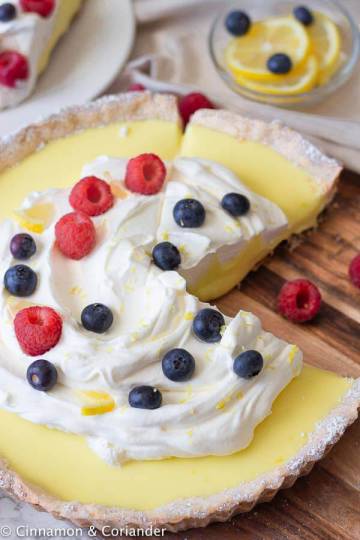 overhead shot of a classic French lemon tart topped with whipped cream and berries