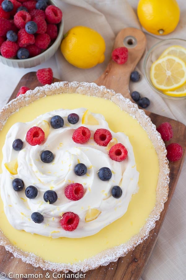 overhead shot of a healthy French lemon tart decorated with whipped cream and fresh berries