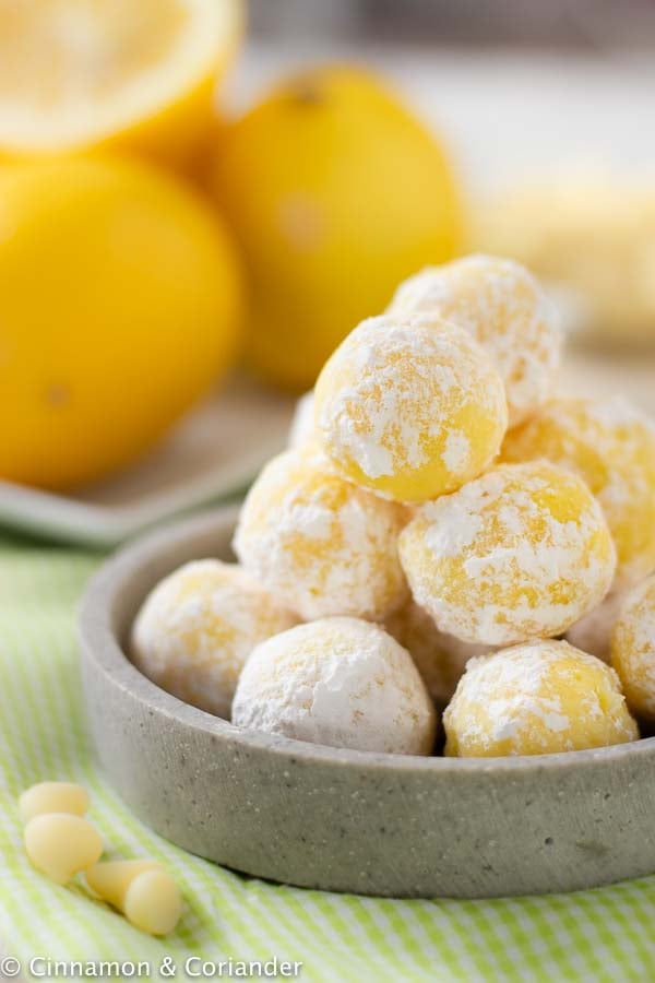 easy no bake white chocolate lemon truffles rolled in powdered sugar stacked 