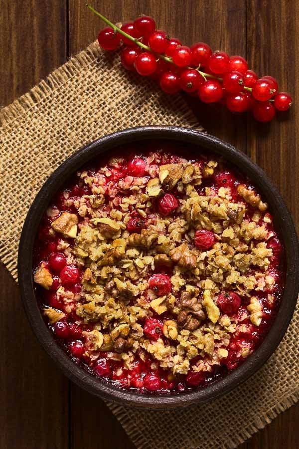 a brown bowl with vegan red currant crumble with walnuts and oats