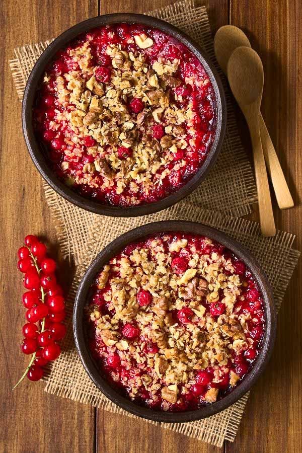 overhead shot of two bowls with vegan red currant crumble with oat walnut crumble topping 