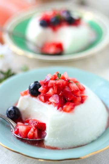 Greek yogurt panna cotta topped with thyme macerated berries on a blue plate