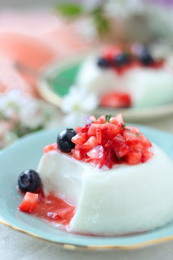 berry topped panna cotta with Greek yogurt on a blue saucer