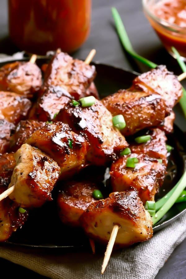 close-up of Penang Malaysian grilled pork satay skewers on a black plate 