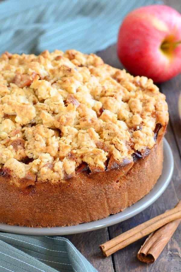 Authentic German Apple Cake with Streusel Topping on a cake plate with cinnamon sticks on the side