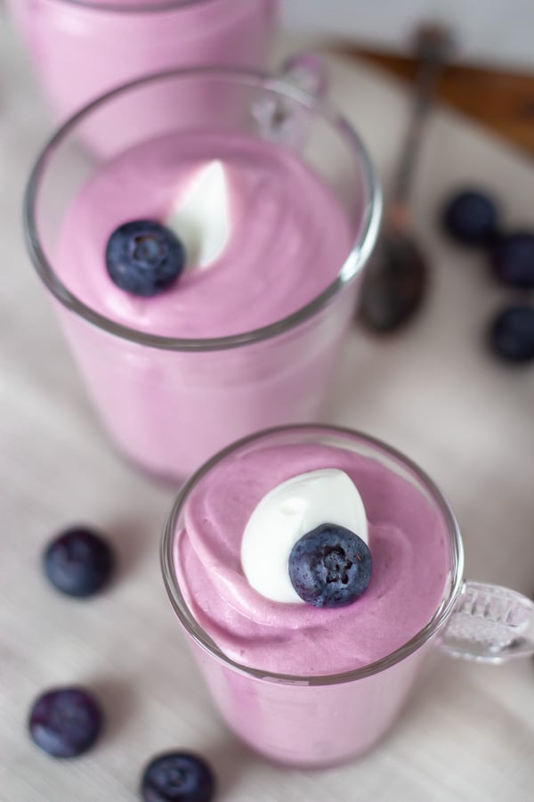 overhead shot of two jars with healthy sugar-free blueberry cheesecake mousse 