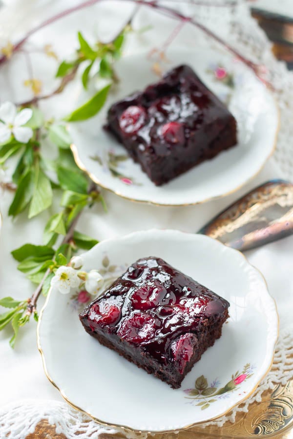 zwei saftige Kirsch Brownies mit Kakao auf Kuchentellern mit Kirschblüten 