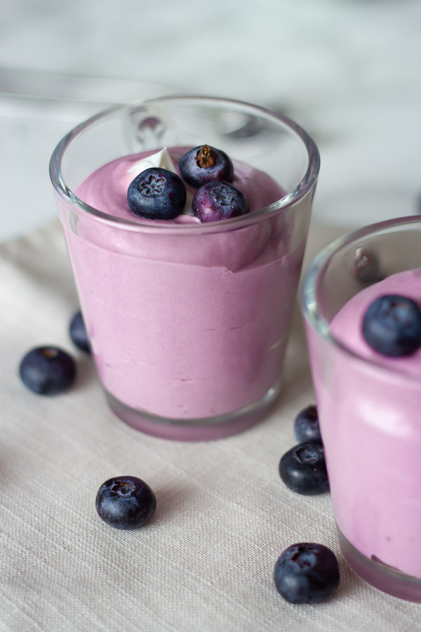 two jars of No Bake Vegan Blueberry Mousse topped with fresh blueberries 