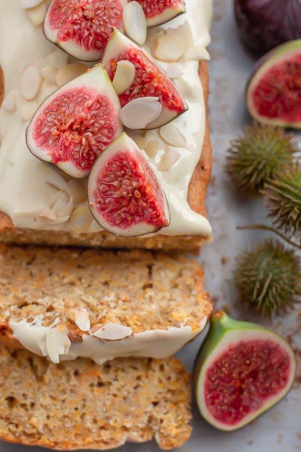 overhead shot of a sliced loaf of cardamom almond flour cake topped with fresh figs 