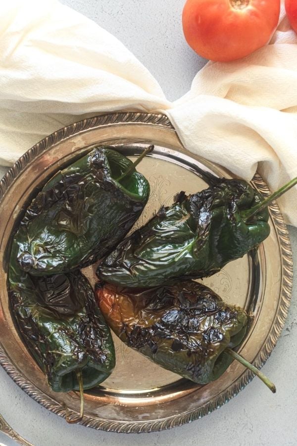 roasted charred poblano chiles on a silver plate 