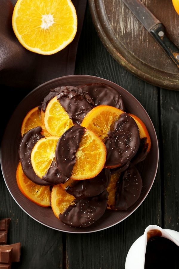 chocolate dipped orange slices on a brown plate 