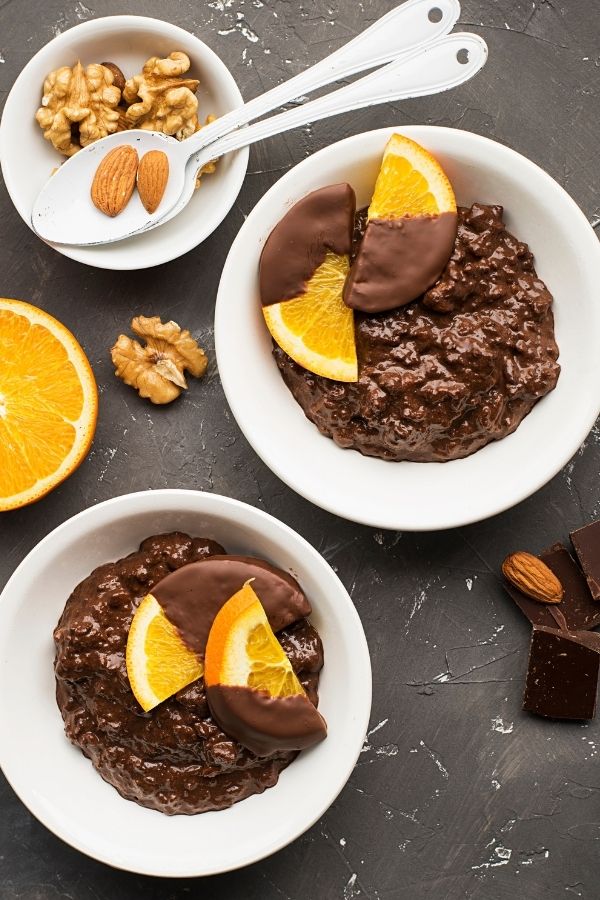 two bowls of healthy vegan chocolate orange porridge decorated with chocolate dipped orange slices