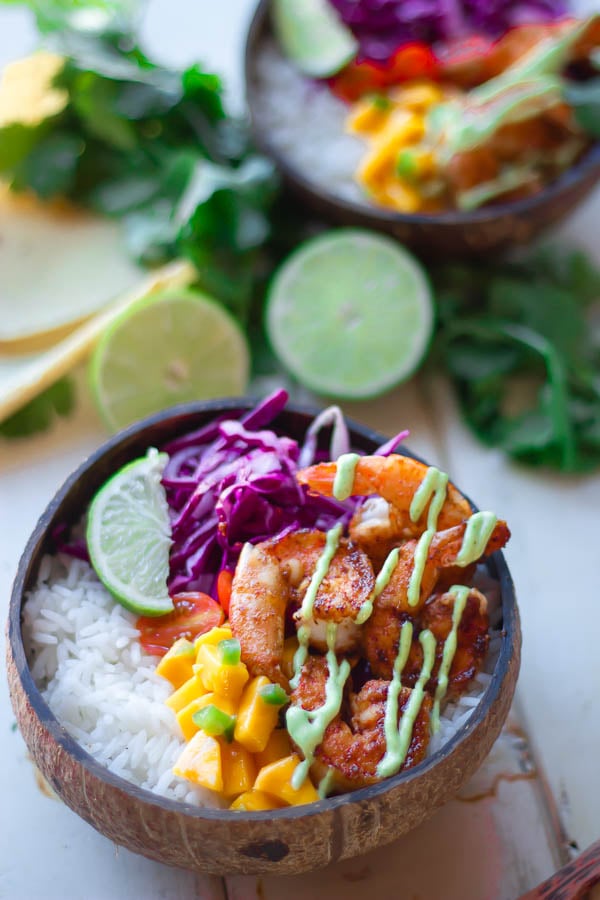 shrimp taco bowl served in a coconut bowl with jasmine rice, red slaw, mango salsa and cilantro lime mayo