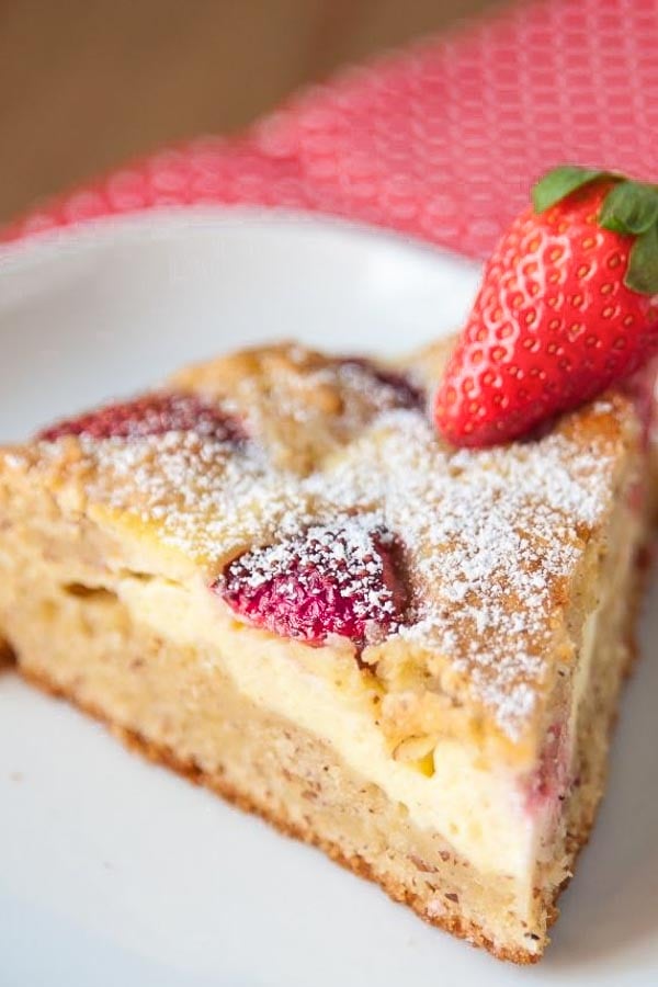 close-up of a slice of fresh strawberry cake with cheesecake swirl dusted with icing sugar