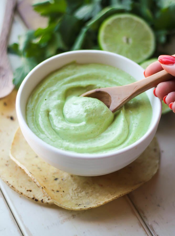 a small bowl of cilantro lime mayo with a wooden spoon 