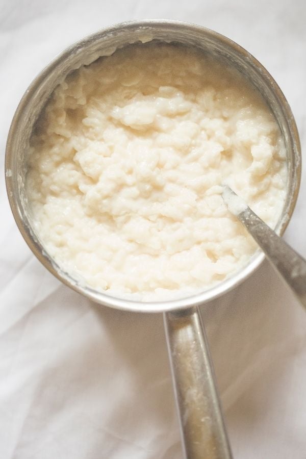 creamy lemon rice pudding being stirred in a pot with condensed milk and butter