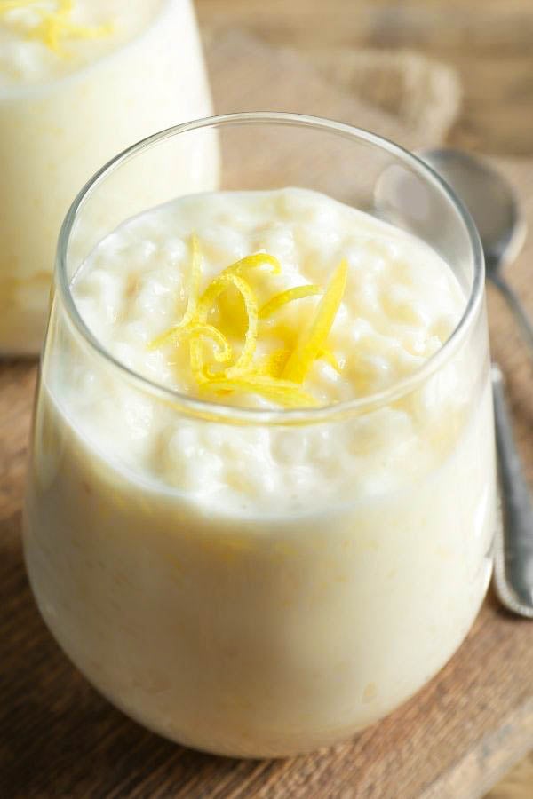Omas Milchreis mit Ei und Butter serviert in einem Dessert Glase mit Zitronenschale dekoriert