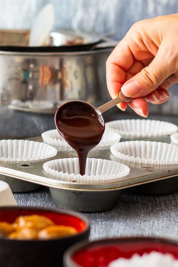 dark chocolate being drizzled into paper cups to make vegan salted caramel cups 