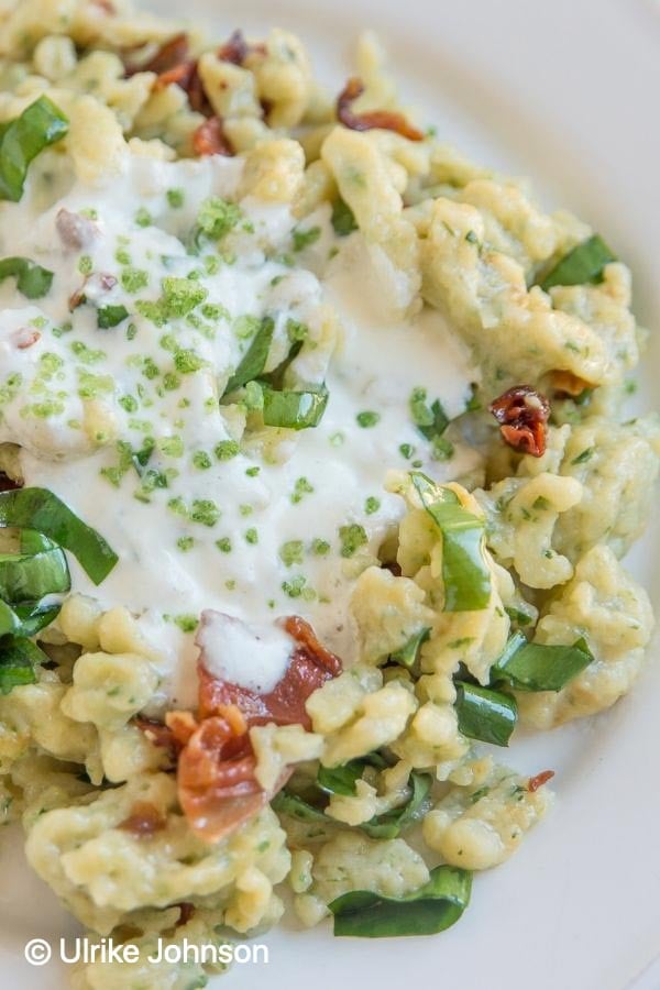 selbstgemachte Bärlauchspätzli mit knusprigen Speckwürfeln und saurer Sahne serviert