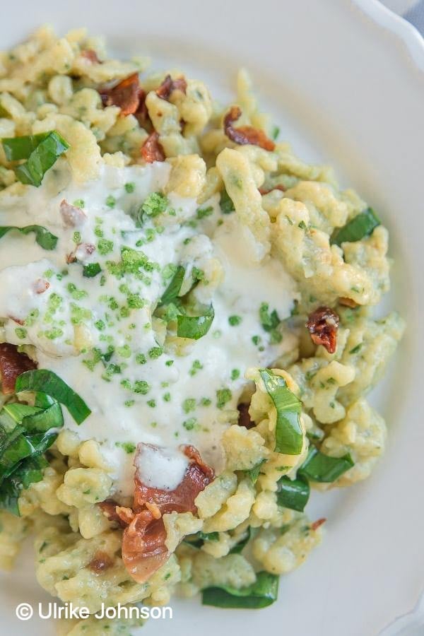 Homemade Traditional German spätzle egg noodles served on a plate with bacon and wild garlic