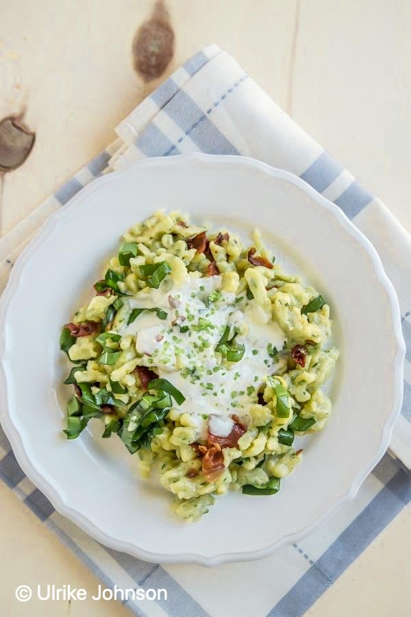 overhead shot of a plate with German spätzle with wild garlic, bacon and cheese sauce