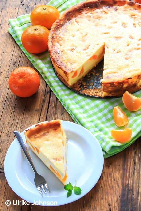 a slice of German cheesecake with mandarin oranges next to a whole German cheesecake