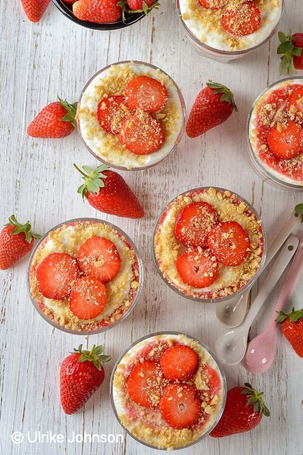 overhead shot of strawberry mascarpone desserts decorated with fresh strawberries and cookie crumbs 