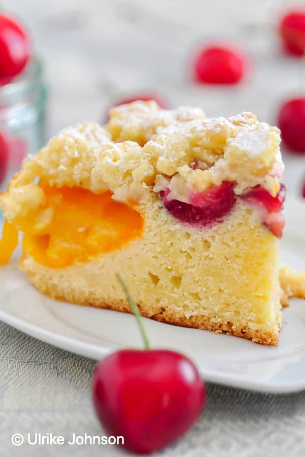 a slice of Austrian Fresh Apricot Crumble Cake with cherries topped with streusel 