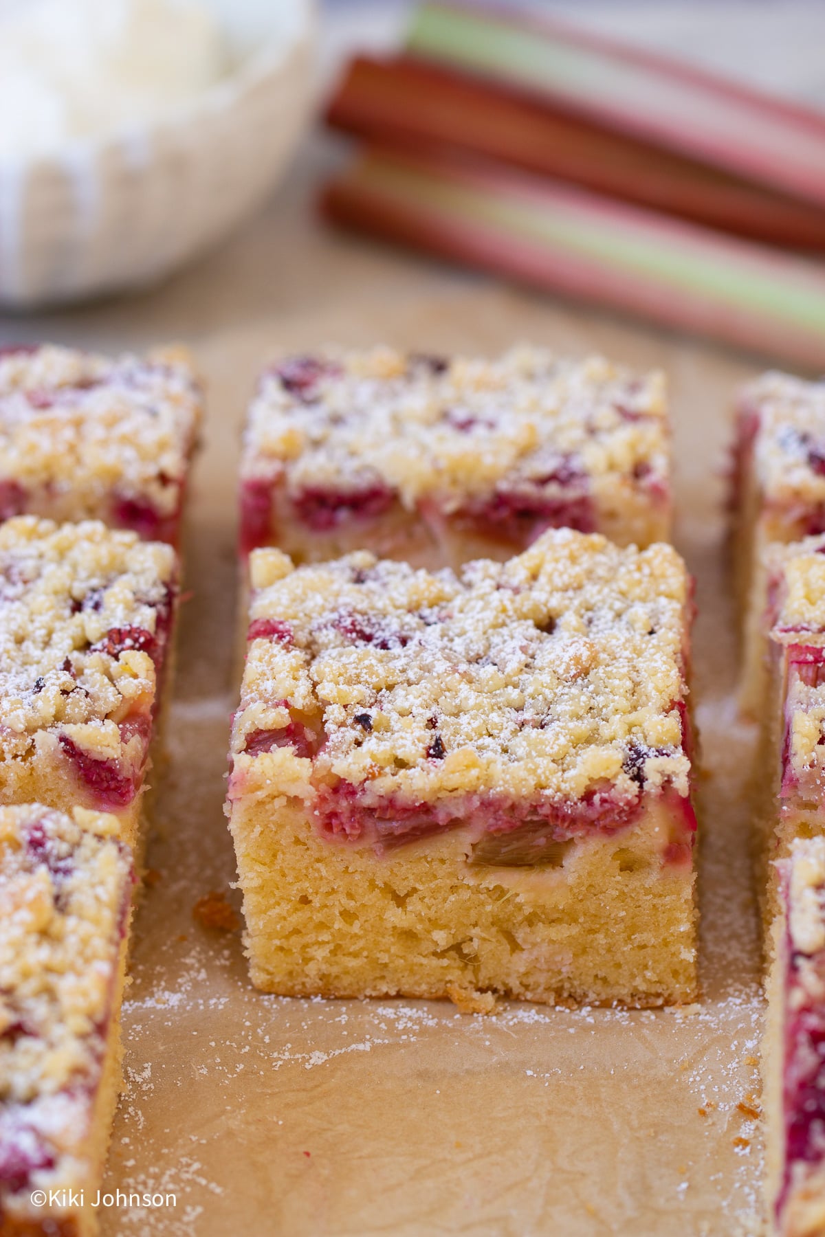 Himbeer Rhabarber Streuselkuchen mit frischem Rhabarber im Hintergrund 
