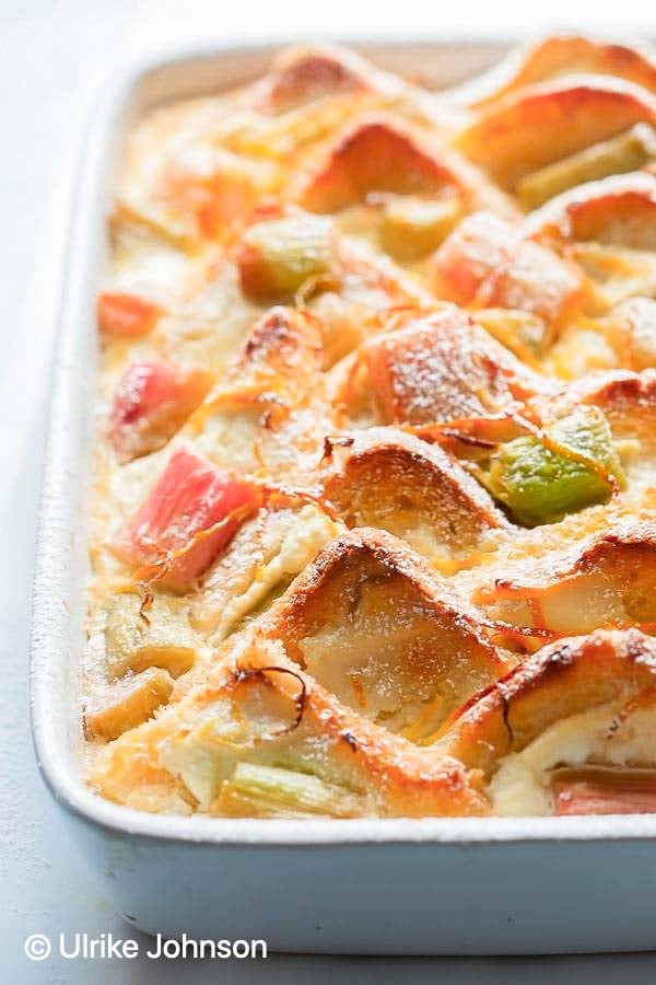 side view of rhubarb bread pudding dusted with icing sugar