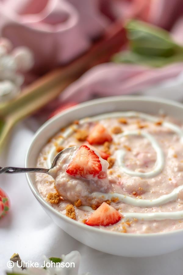 Rhubarb Strawberry Porridge topped with fruit, cookie crumbs and a cheesecake swirl 