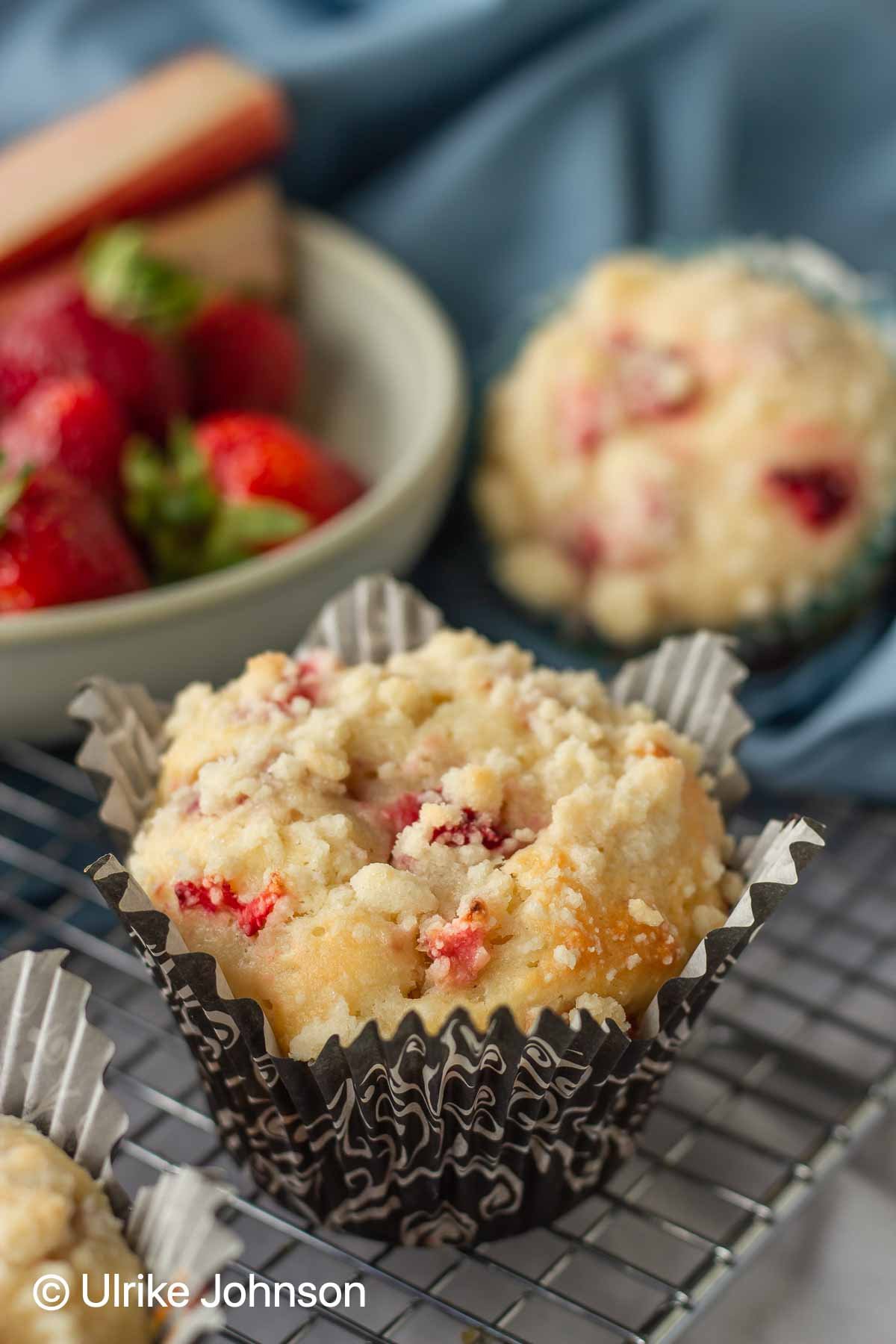 Strawberry Rhubarb Streusel Muffins with Sour Cream on a cooling rack with fresh strawberries in the background