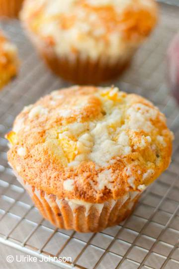 peach cobbler muffins with streusel topping on a wire rack