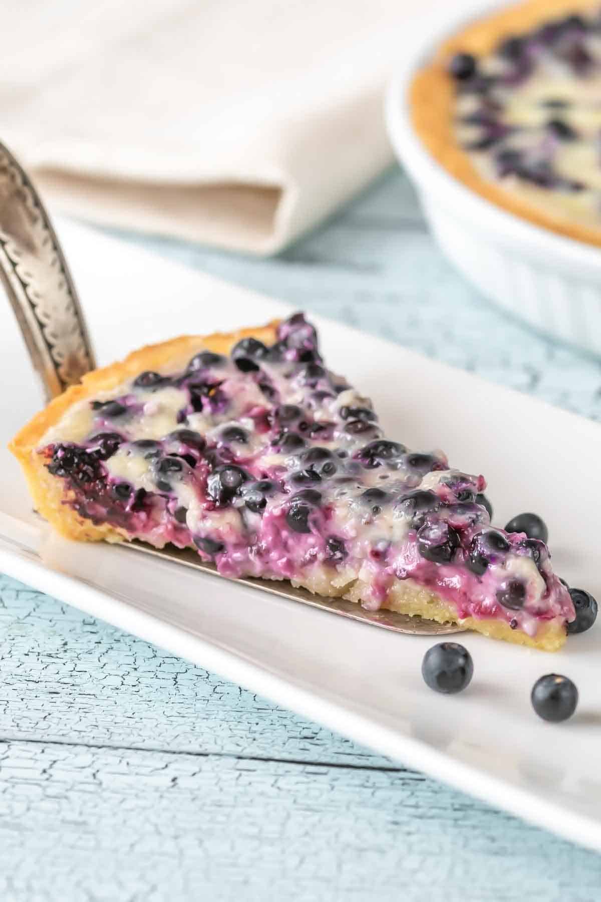 ein Stück Finnischer Blaubeer Tarte mit Vanillecreme auf einem Kuchenteller