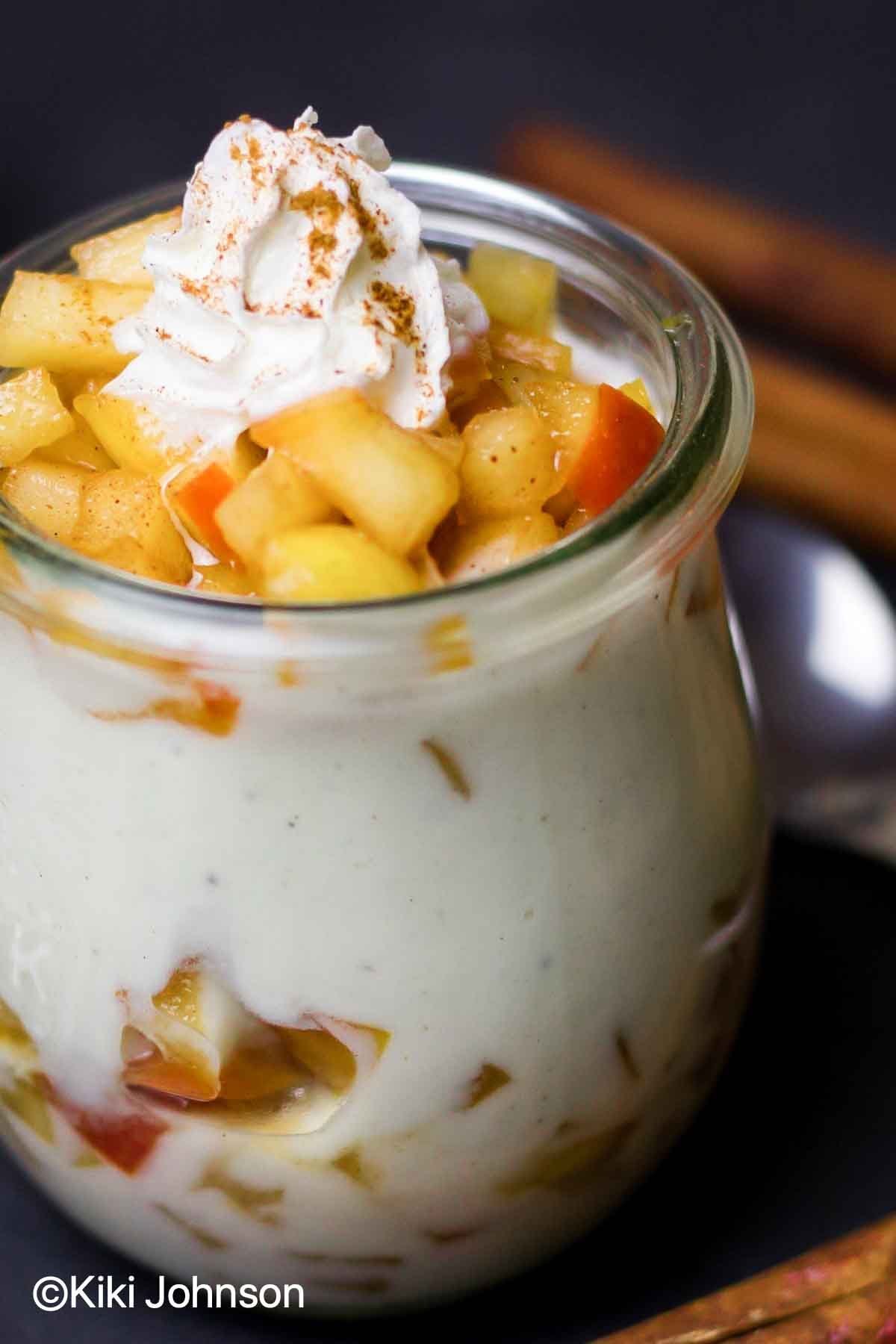 apple cinnamon parfaits in a small mason jar topped with whipped cream 