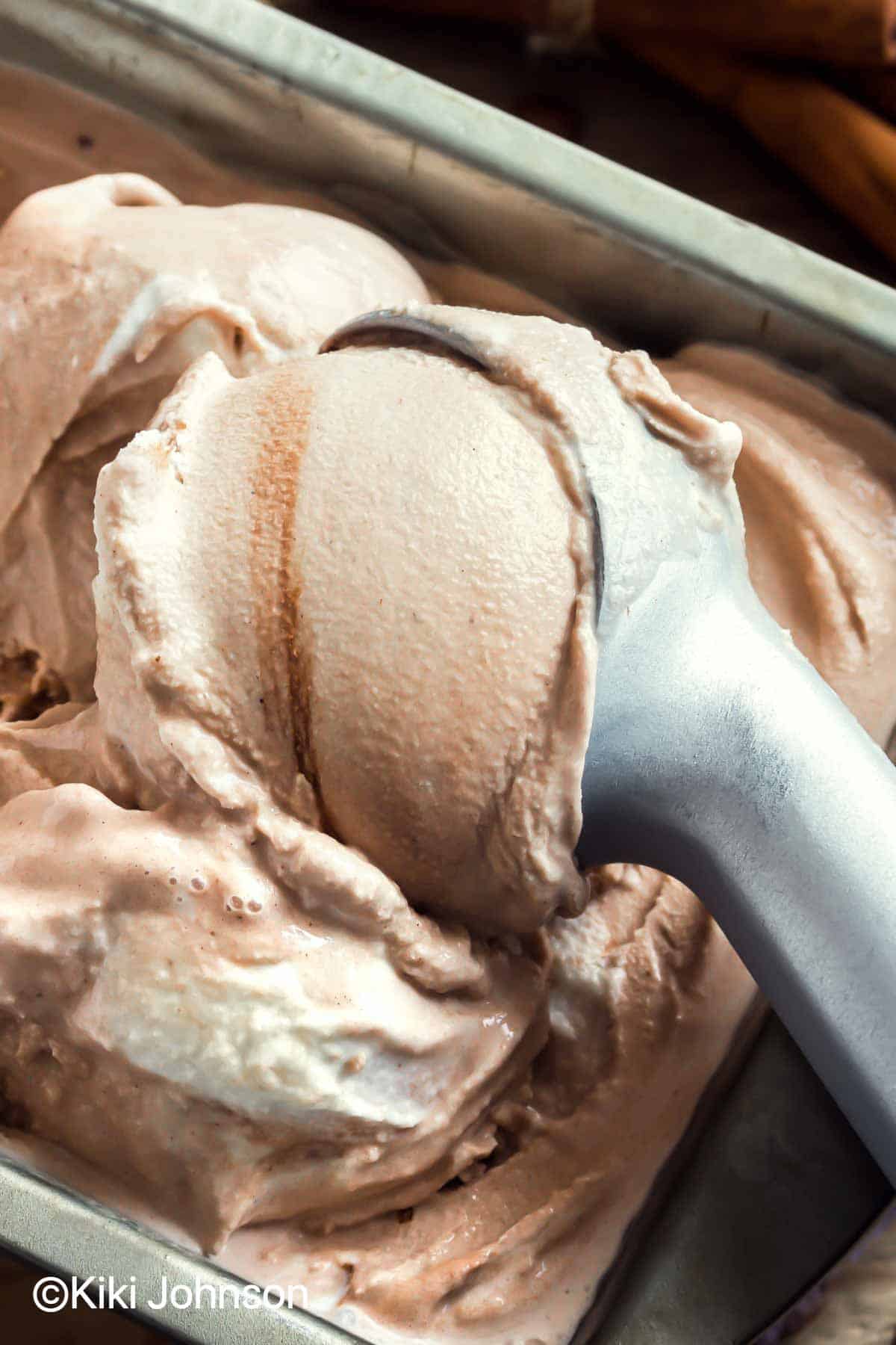 cinnamon swirl ice cream being scooped out if the container with an ice cream scoop 