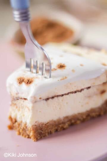 a slice of cinnamon roll cheesecake topped with cream cheese frosting