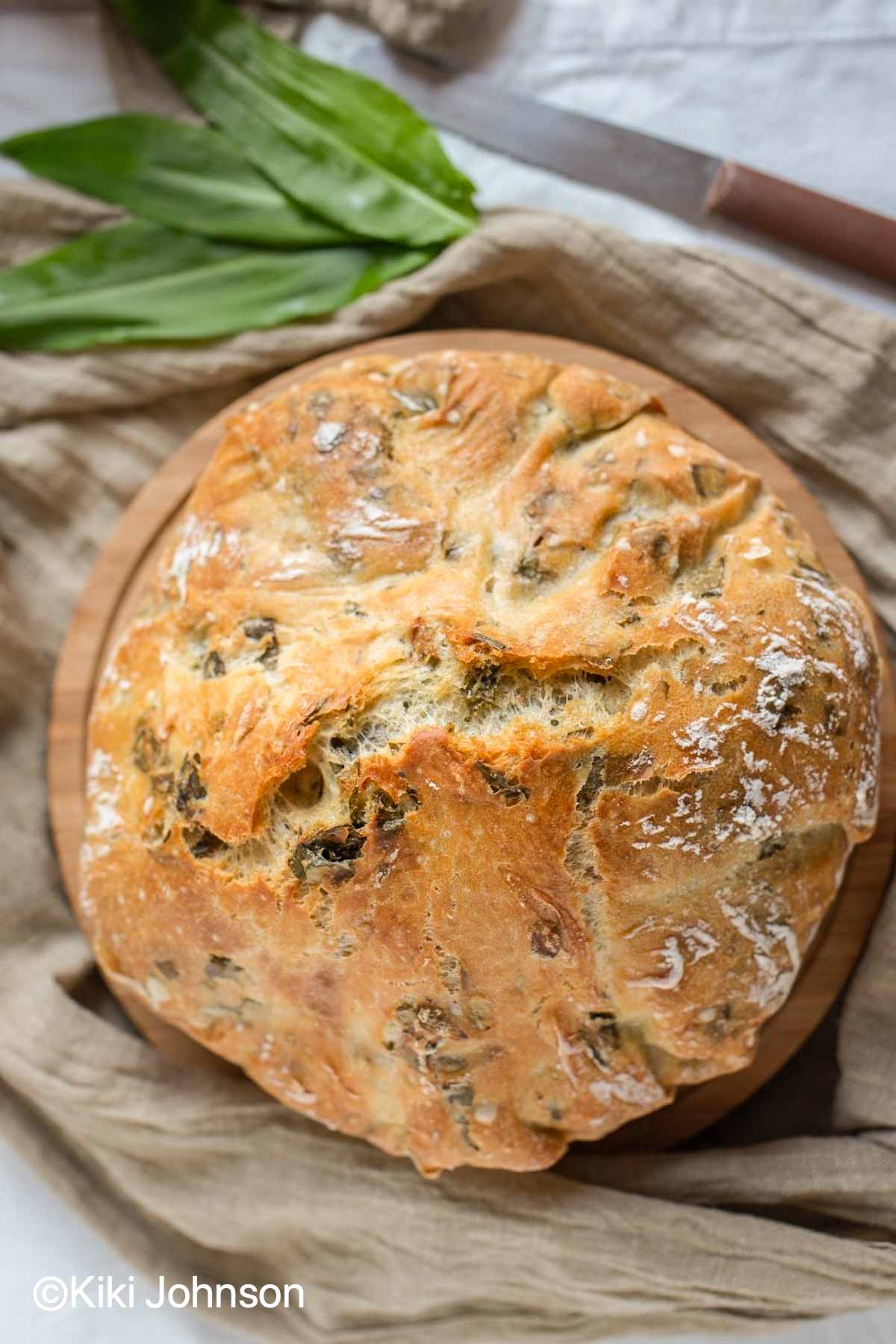 a loaf of wild garlic bread with garlic leaves on the side 
