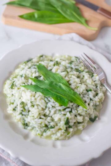 a plate of wild garlic risotto garnished with fresh wild garlic leaves