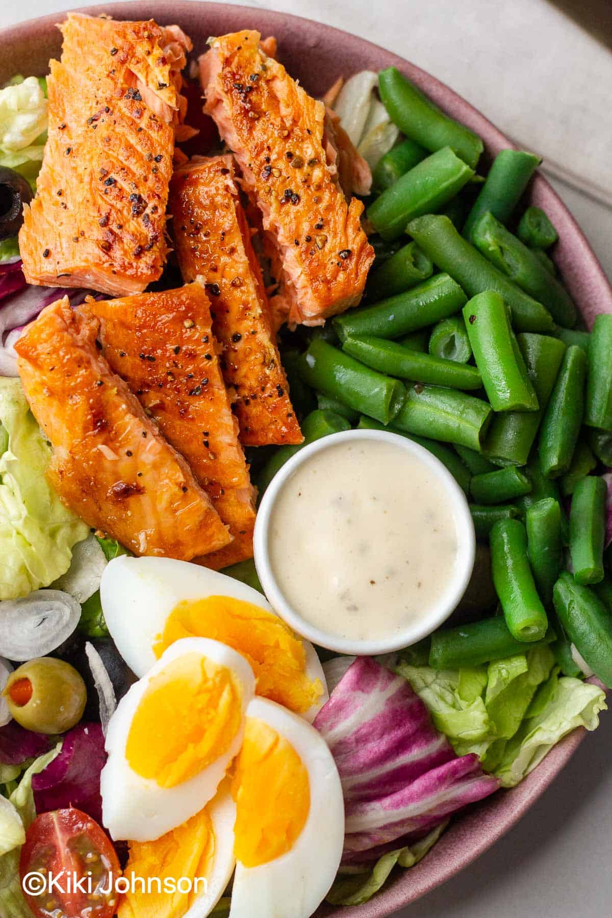 Nicoise Salat mit gebratenen Lachs Streifen Ei und Bohnen mit Nicoise Dressing auf einem Salat Teller