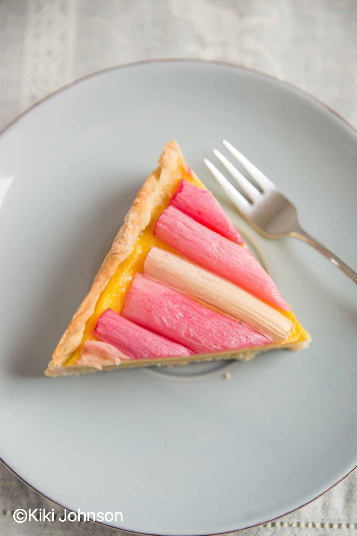 a slice of rhubarb and custard tart on a blue plate