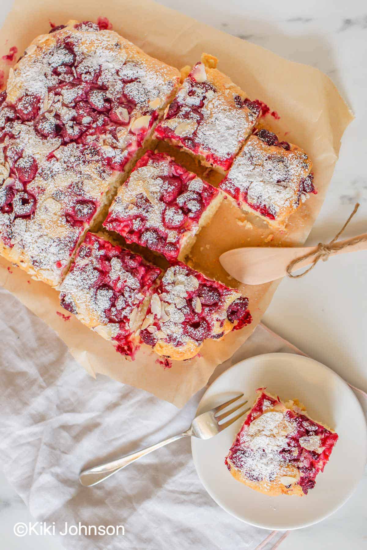 German Raspberry Cake cut into squares on a sheet of parchment paper.