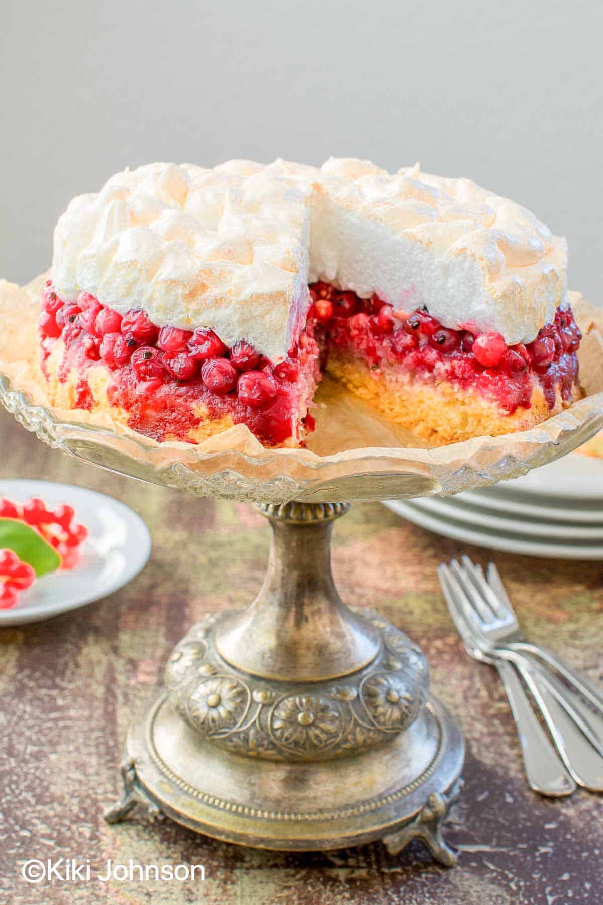 German Meringue Cake with red currants and meringue on a silver cake stand 