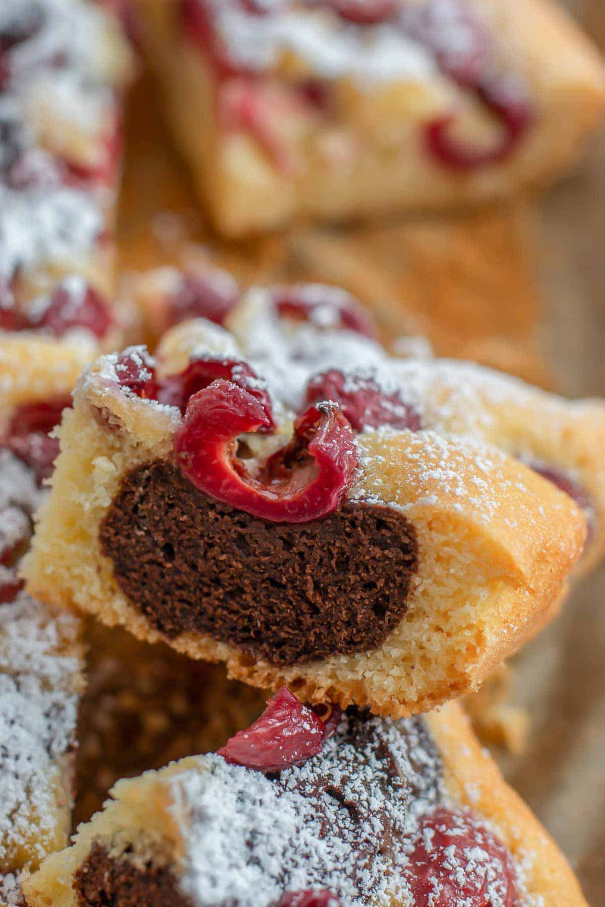 zwei Stücke Marmorkuchen mit Kirschen vom Blech auf Backpapier gestapelt